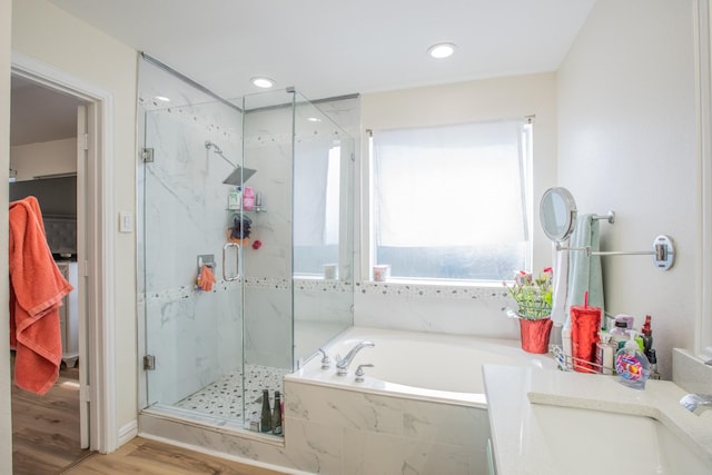 full bath with recessed lighting, wood finished floors, a marble finish shower, a sink, and a garden tub