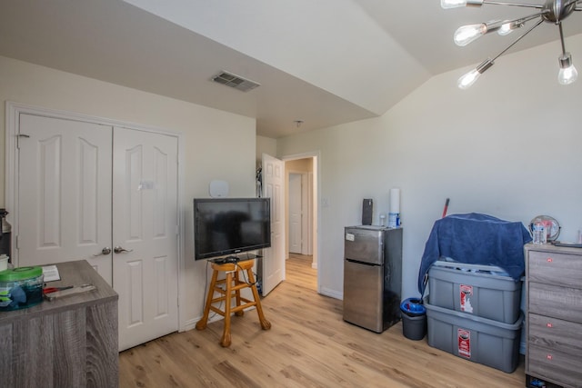 interior space with vaulted ceiling, light wood-style floors, visible vents, and baseboards