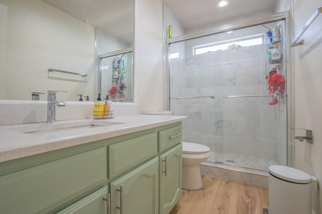 full bathroom with a stall shower, toilet, recessed lighting, wood finished floors, and vanity