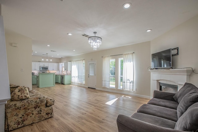 living room with recessed lighting, a glass covered fireplace, light wood-type flooring, and visible vents