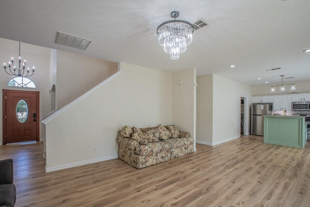 interior space with light wood-style floors, visible vents, baseboards, and an inviting chandelier
