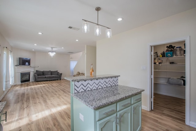 kitchen with baseboards, light wood-style flooring, visible vents, and pendant lighting