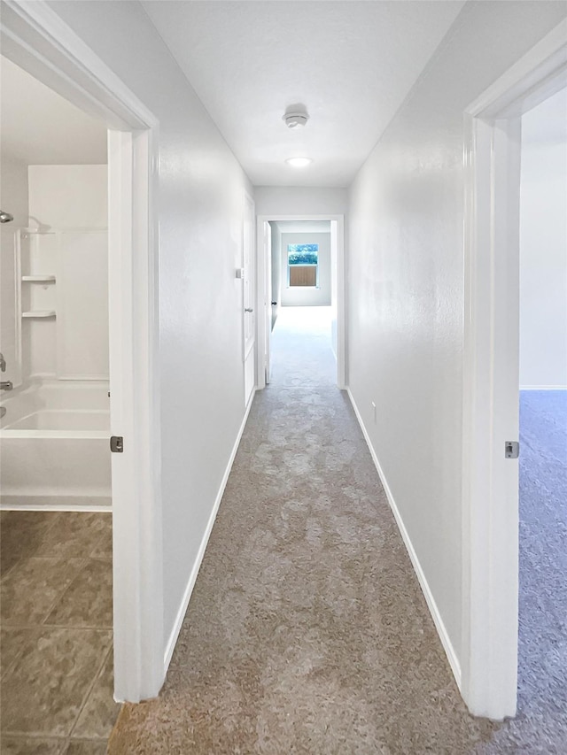 hall featuring carpet flooring and baseboards