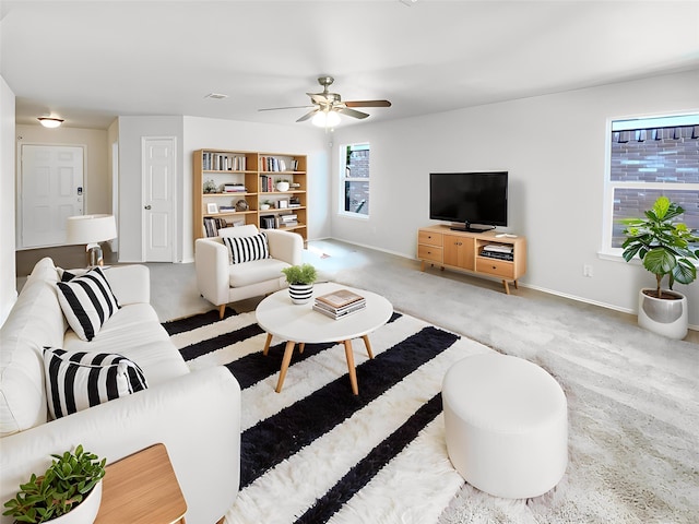 carpeted living area featuring ceiling fan and baseboards