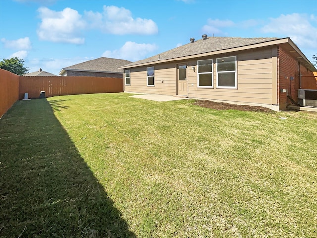 rear view of house with a yard, a patio, a fenced backyard, and a shingled roof