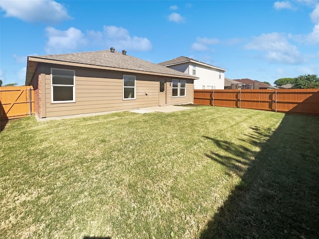 rear view of property with a fenced backyard, roof with shingles, a patio area, and a yard