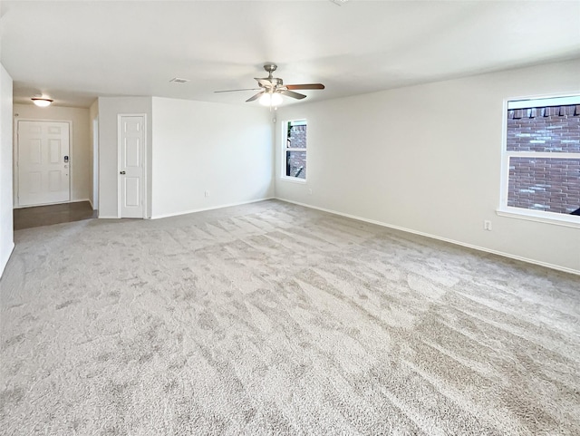 unfurnished room with carpet, a ceiling fan, and baseboards