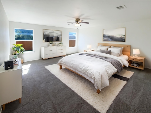 bedroom featuring dark colored carpet, visible vents, ceiling fan, and multiple windows