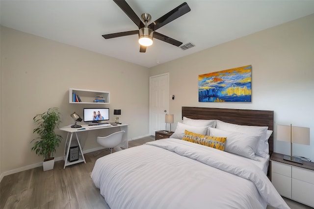 bedroom featuring baseboards, a ceiling fan, wood finished floors, and visible vents