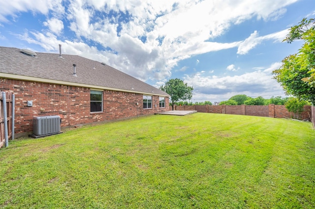 view of yard with a fenced backyard, central air condition unit, and a deck