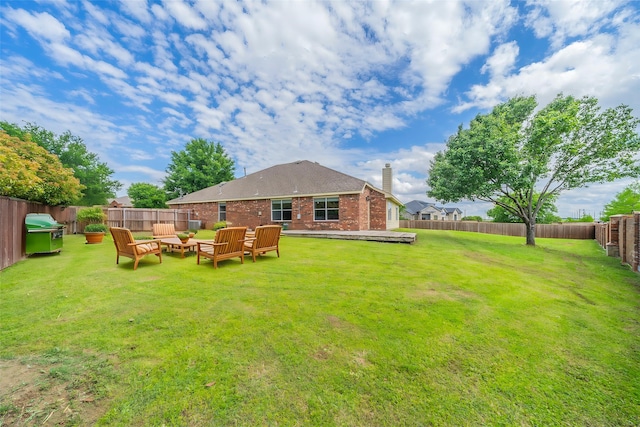 rear view of property featuring brick siding, a yard, a fenced backyard, and a chimney