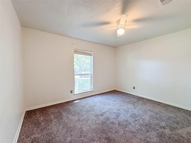 unfurnished room with ceiling fan, baseboards, dark colored carpet, and a textured ceiling