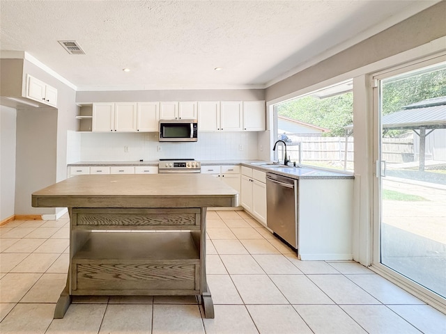 kitchen with stainless steel appliances, open shelves, visible vents, a sink, and white cabinetry