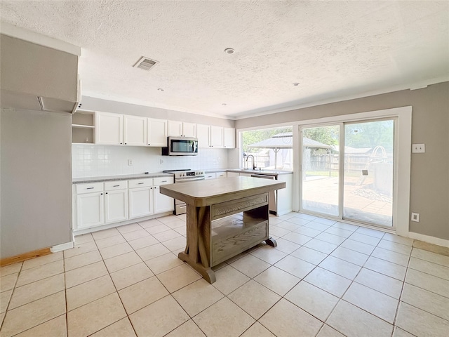 kitchen featuring open shelves, a textured ceiling, appliances with stainless steel finishes, white cabinetry, and visible vents
