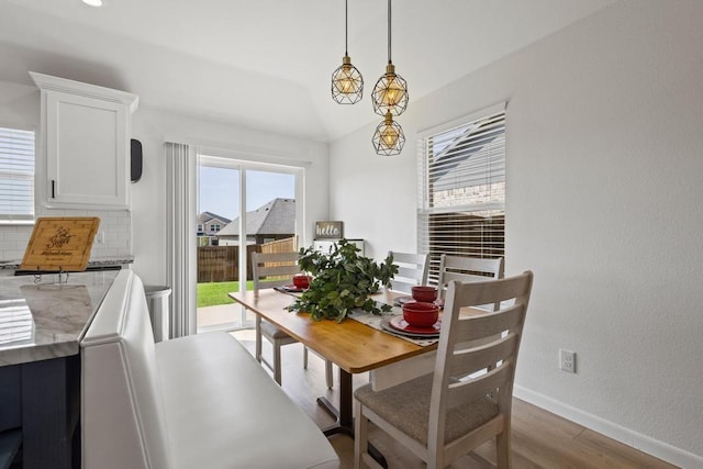 dining area featuring baseboards, wood finished floors, and lofted ceiling