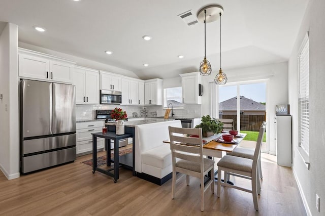 kitchen featuring appliances with stainless steel finishes, tasteful backsplash, white cabinets, and lofted ceiling