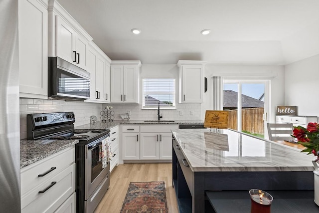 kitchen featuring white cabinetry, stainless steel appliances, light wood-type flooring, and a healthy amount of sunlight