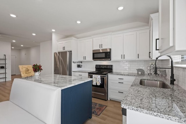 kitchen with a center island, stainless steel appliances, light wood-type flooring, and a sink