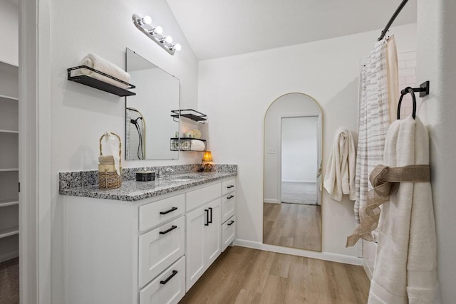 bathroom featuring vanity, curtained shower, baseboards, wood finished floors, and a spacious closet