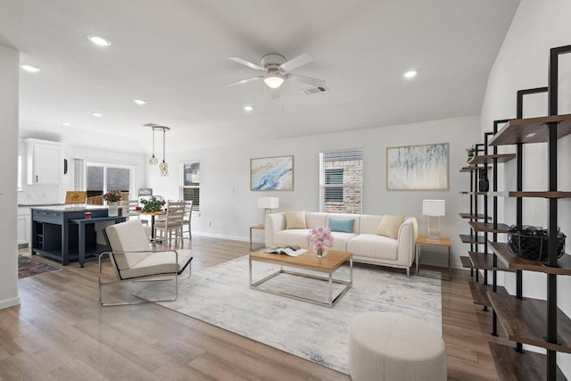 living room featuring baseboards, light wood-type flooring, and a ceiling fan