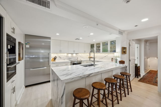 4242 Lomo Alto Dr Unit N12, Highland Park, TX 75219 - kitchen featuring stainless steel appliances, light wood finished floors, decorative backsplash, a breakfast bar area, and recessed lighting