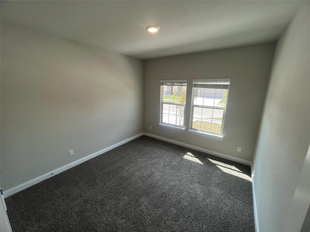 empty room featuring dark carpet and baseboards