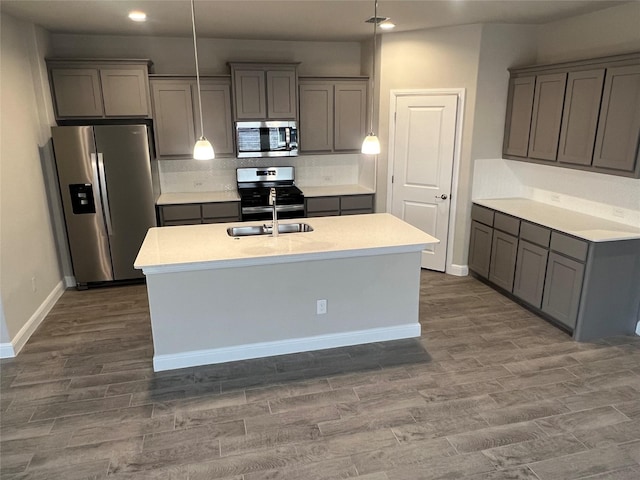 kitchen with recessed lighting, light countertops, gray cabinets, a sink, and appliances with stainless steel finishes