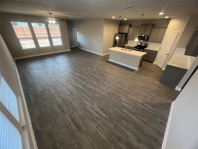kitchen with open floor plan, dark wood-style flooring, appliances with stainless steel finishes, and a sink