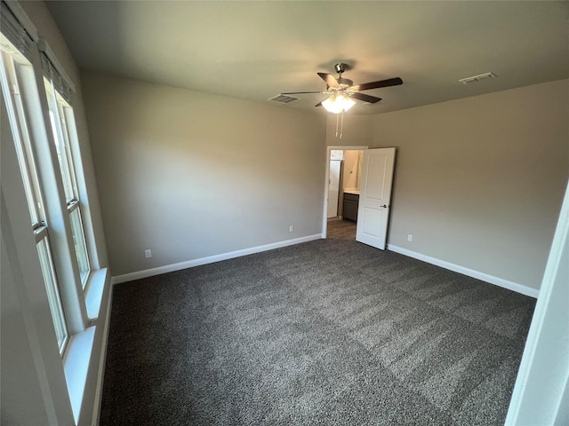 unfurnished bedroom featuring visible vents, dark colored carpet, baseboards, and a ceiling fan