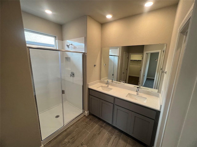 bathroom with a walk in closet, wood finished floors, a sink, and a stall shower