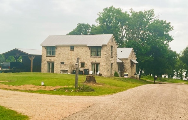 back of property featuring a yard, metal roof, and stone siding