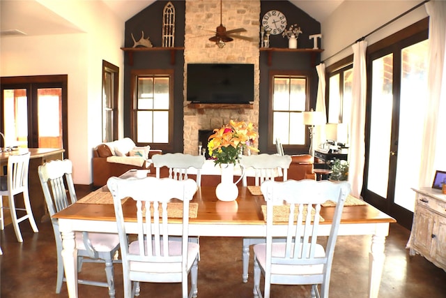 dining area featuring a fireplace, high vaulted ceiling, french doors, and finished concrete flooring