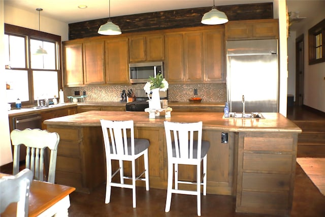 kitchen with a center island, a sink, built in refrigerator, and stainless steel microwave