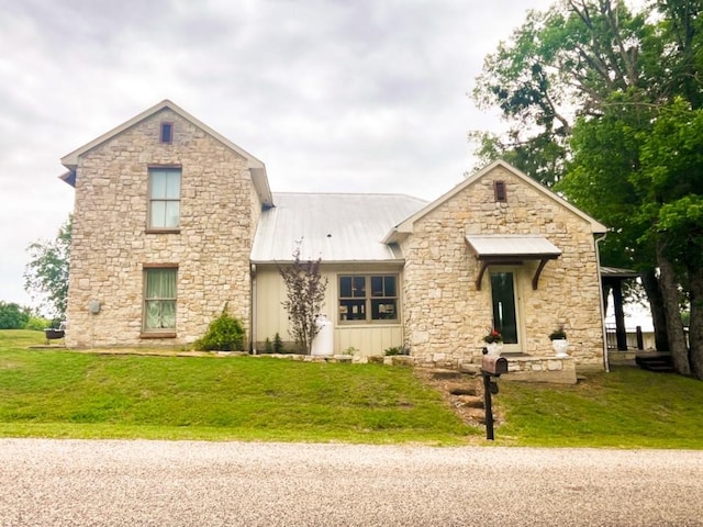 view of front of home with metal roof, stone siding, and a front lawn