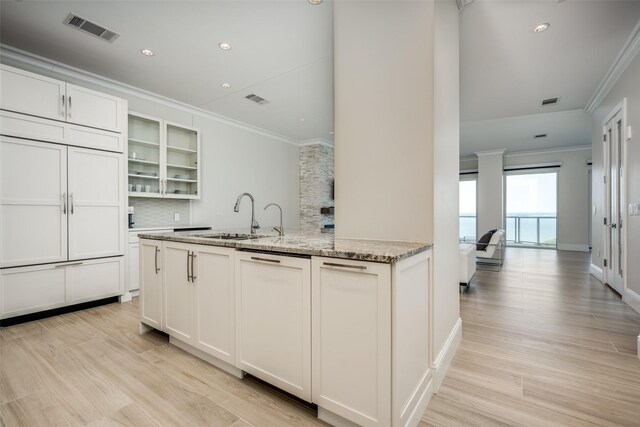 kitchen featuring ventilation hood, a sink, visible vents, built in appliances, and ornamental molding