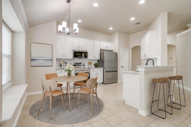 601 Mcneill Ln, Saginaw, TX 76179 - kitchen with stainless steel appliances, arched walkways, decorative backsplash, a chandelier, and recessed lighting