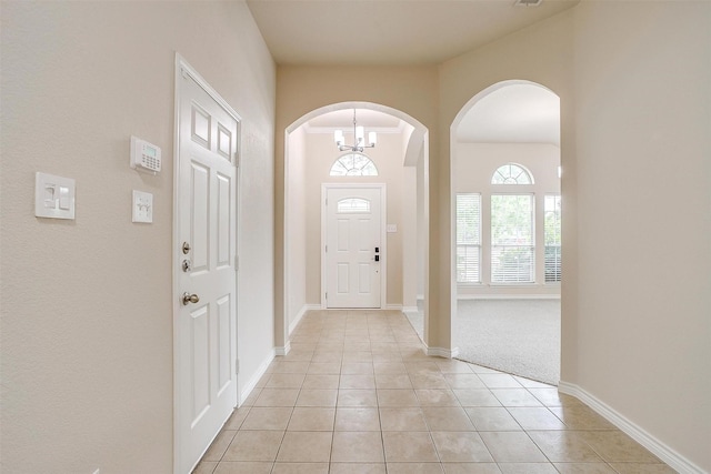 entryway with arched walkways, baseboards, and light tile patterned flooring