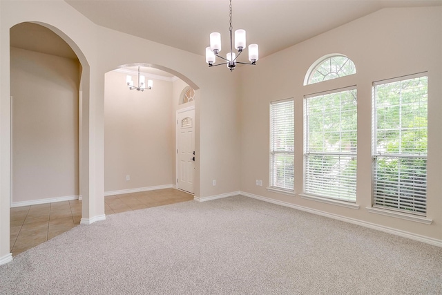 carpeted empty room with arched walkways, tile patterned flooring, baseboards, and a notable chandelier