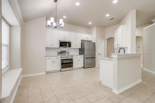 kitchen with decorative backsplash, appliances with stainless steel finishes, arched walkways, a notable chandelier, and light tile patterned flooring