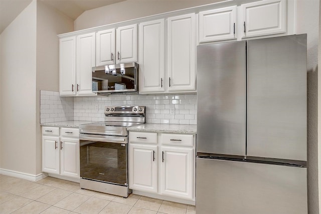 kitchen with white cabinets, light stone counters, appliances with stainless steel finishes, light tile patterned floors, and tasteful backsplash