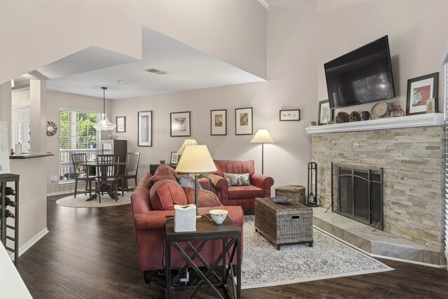 living area with visible vents, baseboards, wood finished floors, and a fireplace
