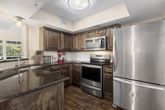 kitchen with dark wood-style floors, visible vents, a sink, dark stone counters, and appliances with stainless steel finishes