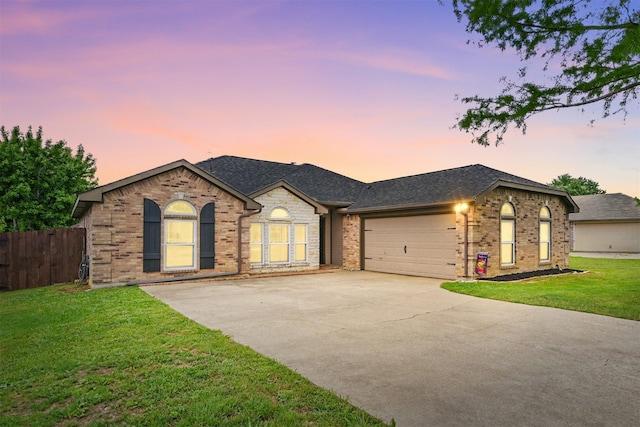 ranch-style home with fence, an attached garage, brick siding, concrete driveway, and a lawn