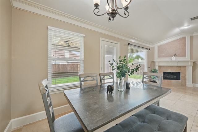 dining area with crown molding, a fireplace, vaulted ceiling, baseboards, and a notable chandelier