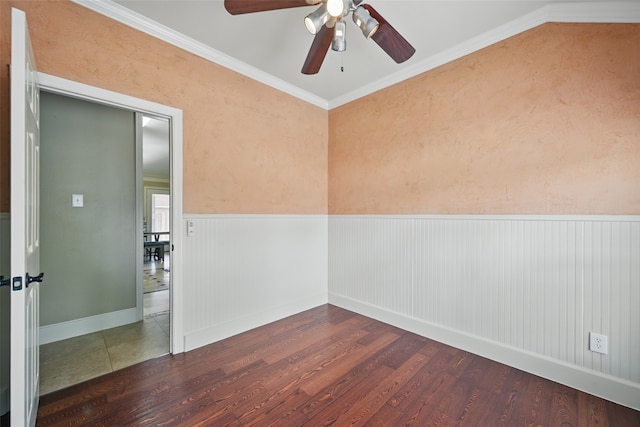 empty room featuring a wainscoted wall, a ceiling fan, baseboards, wood finished floors, and ornamental molding