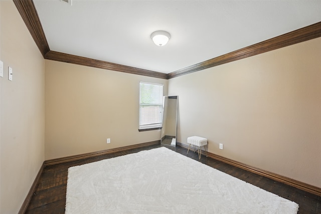 spare room with baseboards, ornamental molding, and dark wood-style floors