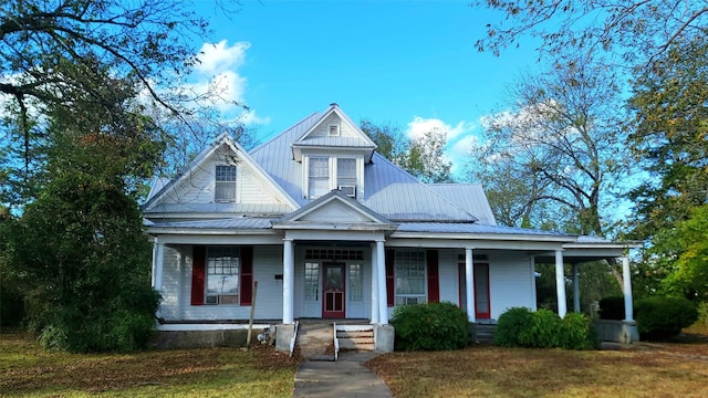 view of front facade with a porch, a front lawn, and metal roof