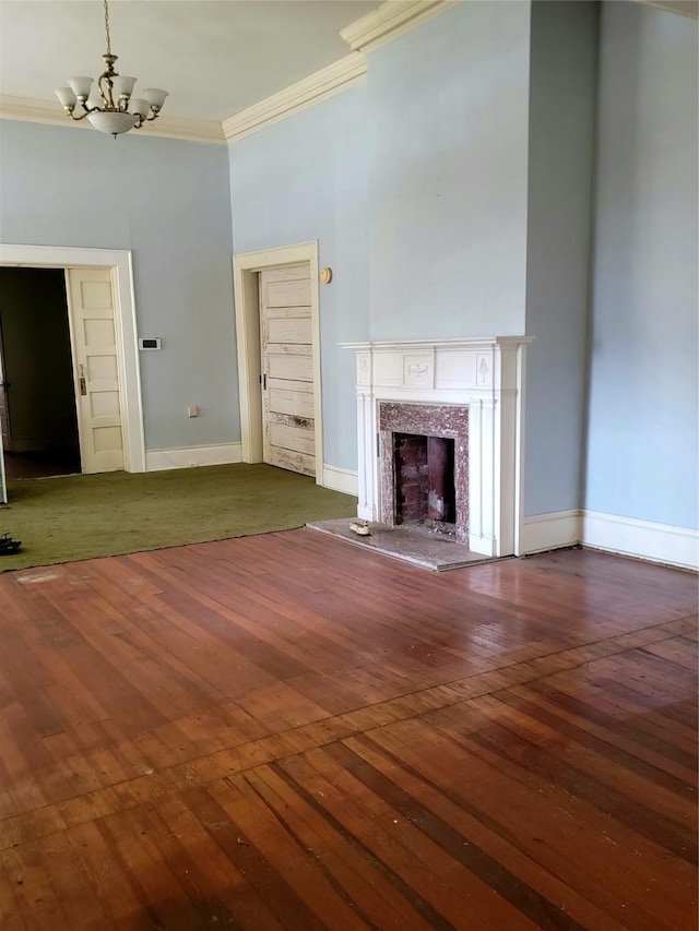 unfurnished living room featuring hardwood / wood-style flooring, baseboards, a chandelier, and ornamental molding