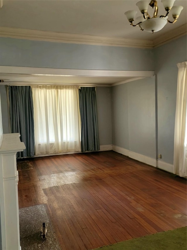 unfurnished room featuring dark wood finished floors, baseboards, ornamental molding, and a chandelier