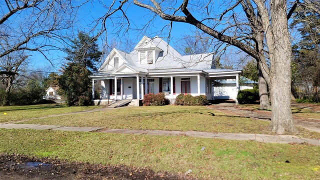view of front of property featuring a front yard, metal roof, and covered porch